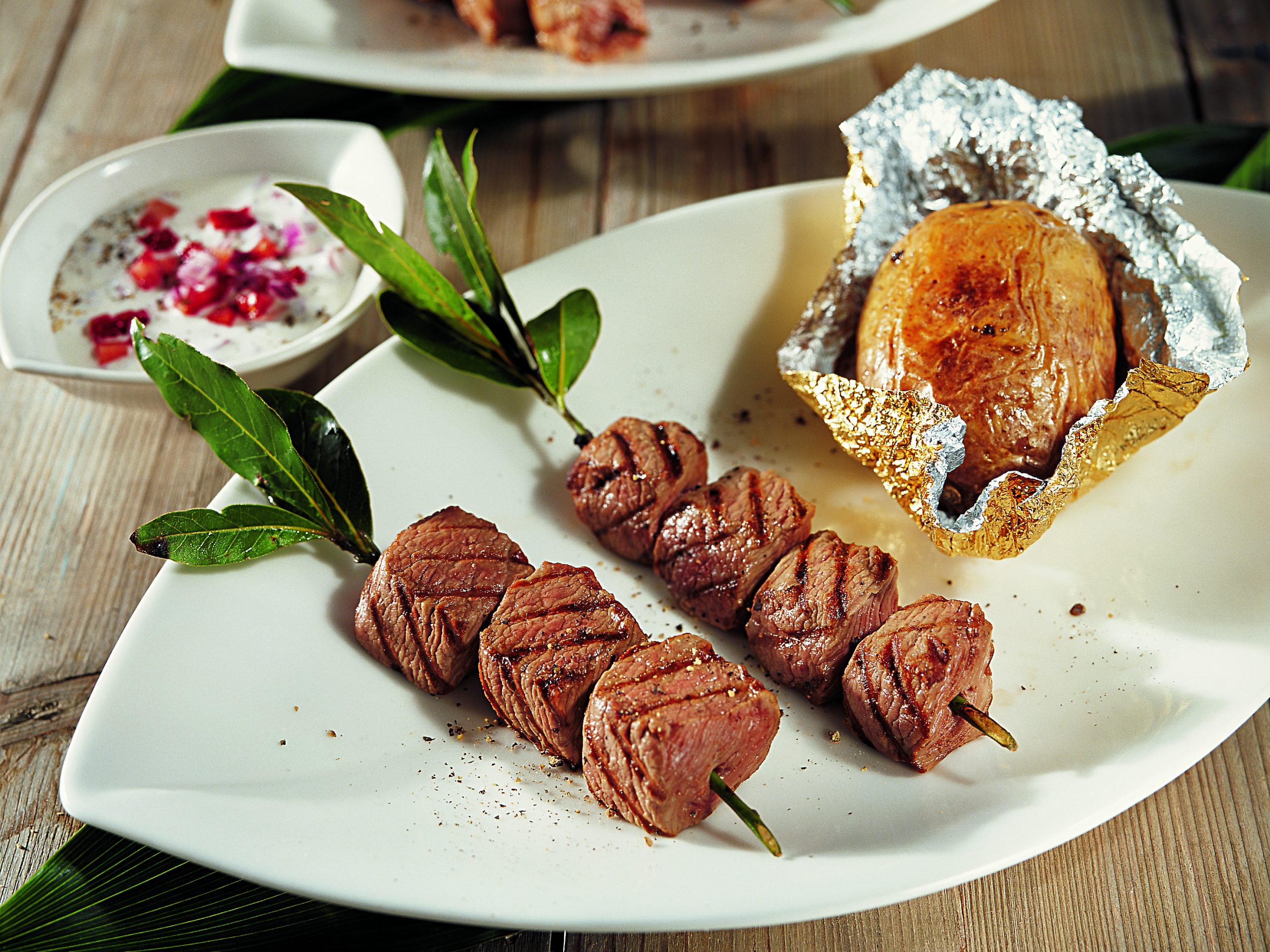 Brochettes d'agneau au barbecue, baked potatoes et sauce