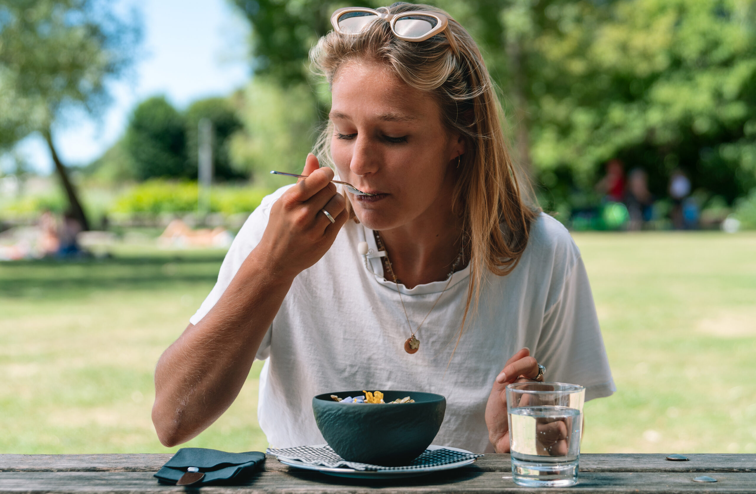 Que manger avant le sport: femme mangeant au parc un repas léger avec des glucides et des protéines.