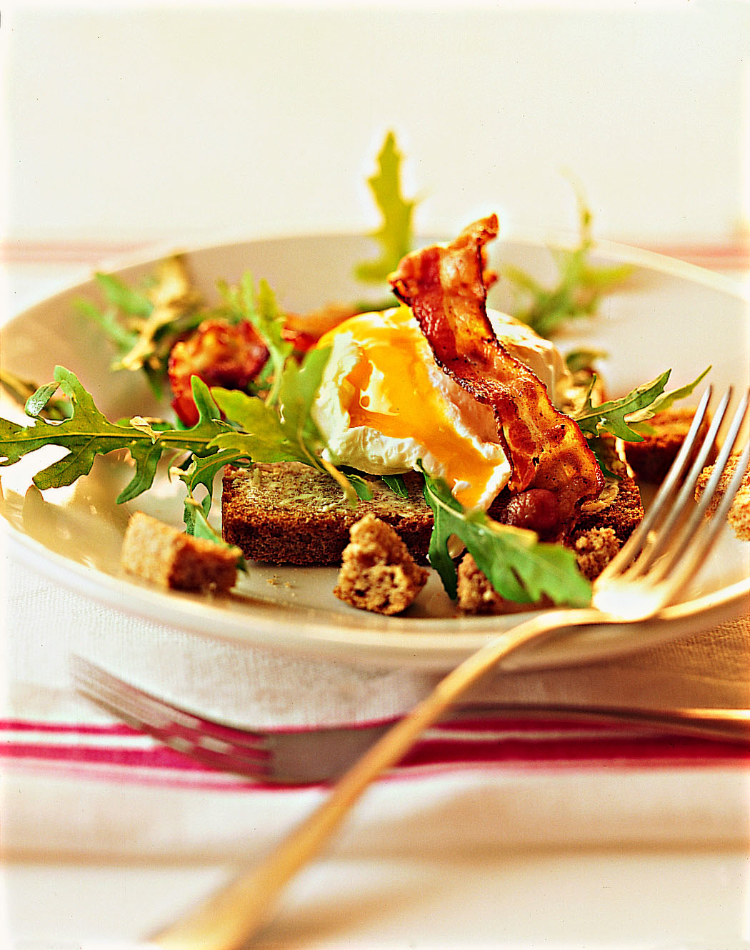 Oeufs pochés au lard sur salade et toast