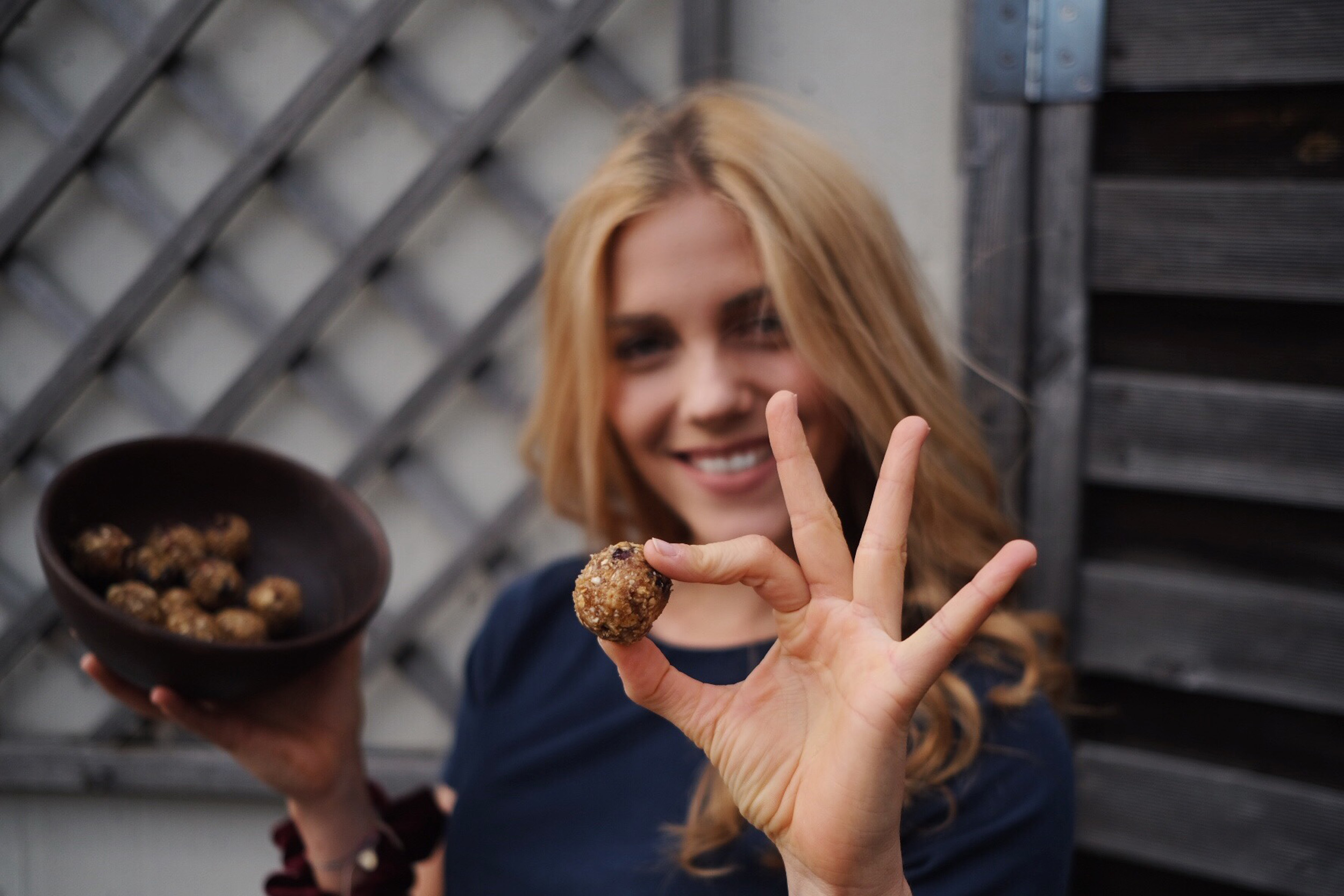 Femme souriante avec des snacks sains en main. Scène invitant à réaliser des collations saines maison.